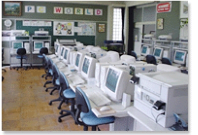PC WORLD　42台のパソコンか並ぶ教室。プロジェクターやビデオなども設置され、授業で活用されている